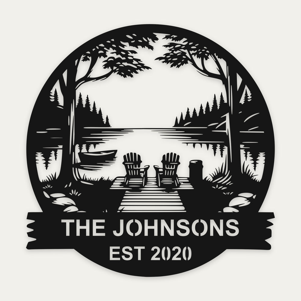 Lakeside dock personalized cottage sign in black steel with two chairs, pines and THE JOHNSONS EST 2020 on the banner